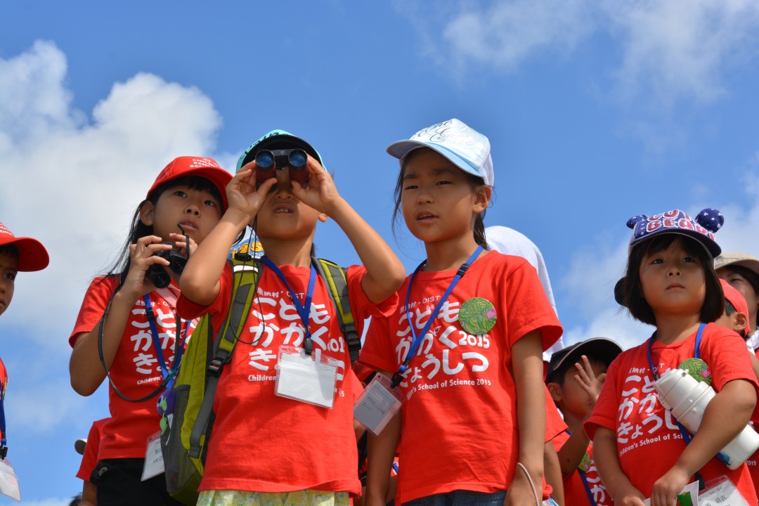 双眼鏡で遠くを見ている子どもたちの写真